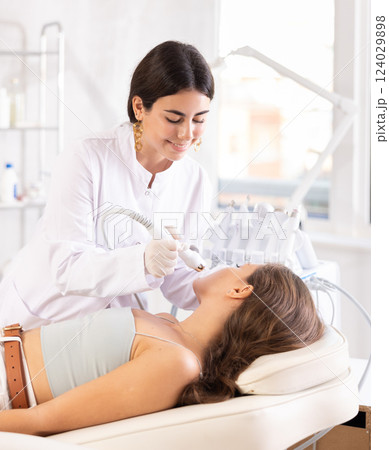 Female doctor making facial beauty procedure with macro molecule atomizing pen 124029898