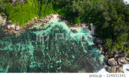 A small cove with clear turquoise water surrounded by rocky shore and lush vegetation. Seychelles, Mahe. 124031341