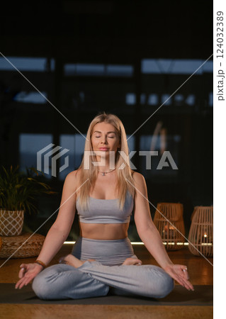 Woman practicing yoga in a serene indoor space surrounded by natural elements during a calm evening meditation session Woman practicing yoga in a serene indoor space surrounded by natural elements during a calm evening meditation session 124032389