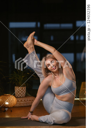 Yoga practitioner demonstrates impressive flexibility in serene studio setting during evening relaxation session with soft lighting Yoga practitioner demonstrates impressive flexibility in serene studio setting during evening relaxation session with soft lighting 124032396