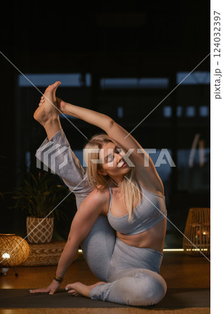 Yoga practitioner demonstrates impressive flexibility in serene studio setting during evening relaxation session with soft lighting Yoga practitioner demonstrates impressive flexibility in serene studio setting during evening relaxation session with soft lighting 124032397