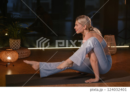 Dynamic yoga practice showcasing a woman performing an advanced pose in a serene and well-lit indoor studio environment during a peaceful evening session 124032401