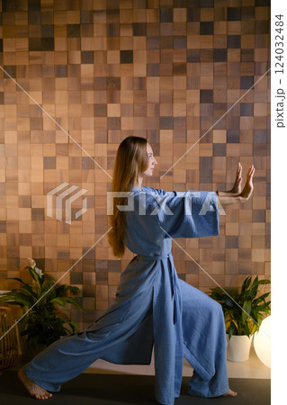 Yoga instructor in blue kimano at fitness gym . The girl does qigong yoga. The exercises are based on the movement of internal energy, the system of channels, energy centers, chakras 124032484
