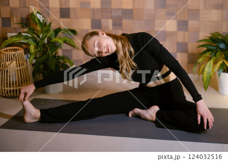 Yoga instructor in black sportswear demonstrates an element of yoga exercise in a fitness gym Yoga instructor in black sportswear demonstrates an element of yoga exercise in a fitness gym 124032516