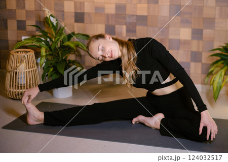 Athletic girl in black sportswear doing yoga in fitness room among indoor green plants Athletic girl in black sportswear doing yoga in fitness room among indoor green plants 124032517