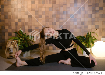 Athletic girl in black sportswear doing yoga in fitness room among indoor green plants Athletic girl in black sportswear doing yoga in fitness room among indoor green plants 124032521