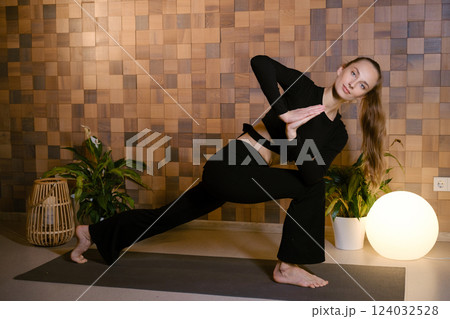 Slender attractive girl in black sportswear doing yoga in fitness room Slender attractive girl in black sportswear doing yoga in fitness room 124032528
