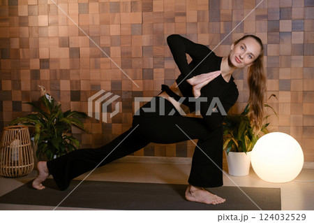 Yoga instructor in black sportswear demonstrates an element of yoga exercise in a fitness gym Yoga instructor in black sportswear demonstrates an element of yoga exercise in a fitness gym 124032529