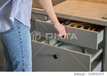 Person opening kitchen drawer with cutlery in cabinet Person opening kitchen drawer with cutlery in cabinet 124032557