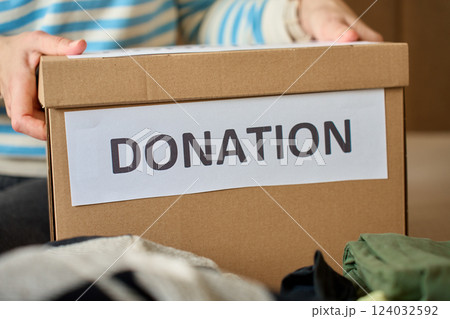 Woman holding donation box with clothes on bed Woman holding donation box with clothes on bed 124032592