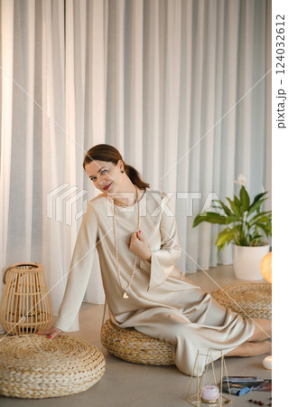 Beautiful Girl in beige dress and beads sitting indoors in front of practice Beautiful Girl in beige dress and beads sitting indoors in front of practice 124032612