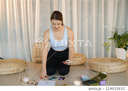 A sporty girl lays out Tarot cards indoors. Tarot cards in the hands of a fortune teller 124032632
