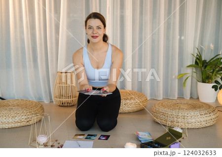 A sporty girl lays out Tarot cards indoors. Tarot cards in the hands of a fortune teller A sporty girl lays out Tarot cards indoors. Tarot cards in the hands of a fortune teller 124032633