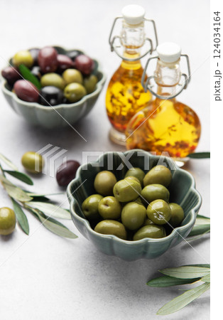 Bowls of green and black olives with olive oil bottles and olive branches on marble table Bowls of green and black olives with olive oil bottles and olive branches on marble table 124034164