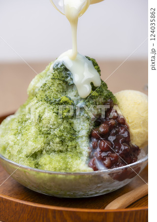 贅沢な抹茶かき氷に練乳をたっぷりとかける 124035862