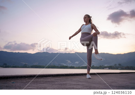 A Woman Doing Yoga Practice by the Lake During a Beautiful Sunset in Natures Splendor 124036110