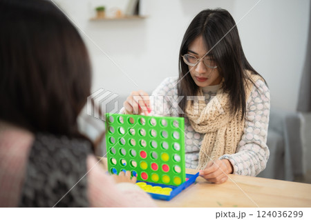 Young women enjoying a game of strategy and skill while playing connect game indoors at a cozy home environment 124036299