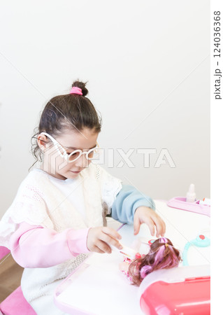 Child playing doctor with doll 124036368