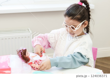 Child playing doctor with doll Child playing doctor with doll 124036371