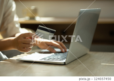 Close up of woman holding a credit card and typing on laptop, internet banking, or secure digital purchases. 124037450