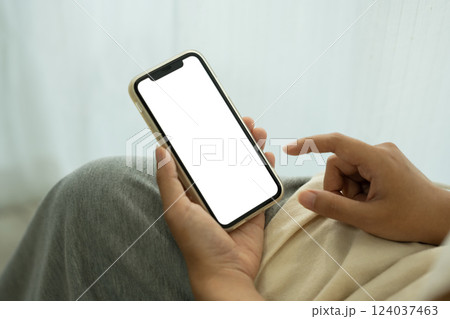 Close up of hands holding smartphone with a blank screen sitting near window with sheer curtains Close up of hands holding smartphone with a blank screen sitting near window with sheer curtains 124037463