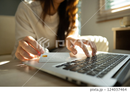 Close up of woman holding a credit card and typing on laptop, internet banking, or secure digital purchases. 124037464