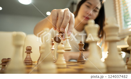 Close up shot of a woman hand placing a chess piece on board 124037482