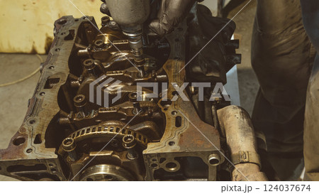 A mechanic working on a car engine in a well-equipped auto repair shop. Car Engine Repair. Mechanic using wrench while working on car engine at garage workshop. Repairing engine in auto repair shop 124037674