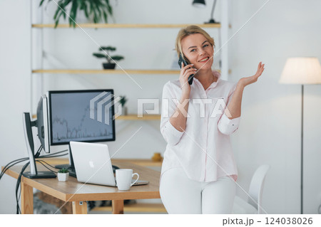 Using smartphone to communicate. Female stock broker in formal wear is working in the office Using smartphone to communicate. Female stock broker in formal wear is working in the office 124038026