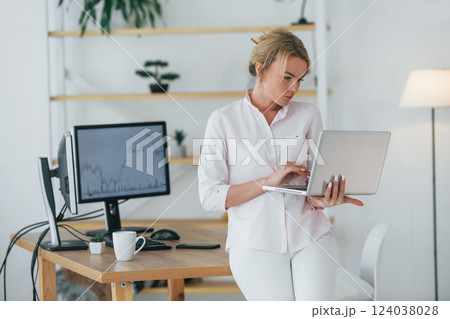 Using smartphone to communicate. Female stock broker in formal wear is working in the office Using smartphone to communicate. Female stock broker in formal wear is working in the office 124038028
