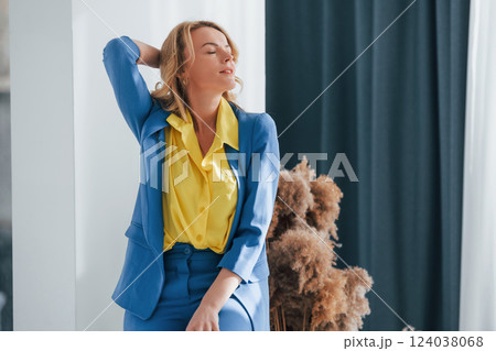 Woman in formal blue and yellow colored trouser suit is indoors 124038068
