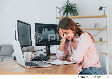 Conception of failure. Female stock broker in casual clothes is working in the office by pc Conception of failure. Female stock broker in casual clothes is working in the office by pc 124038080