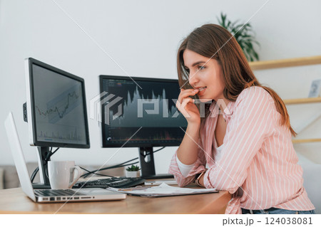 Feels worried. Female stock broker in casual clothes is working in the office by pc 124038081