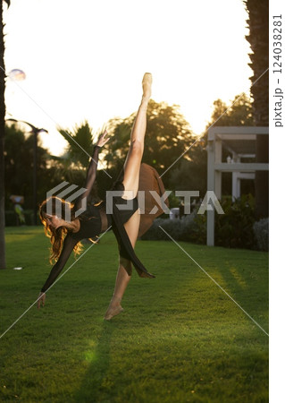 Ballerina performing elegant dance pose outdoors Ballerina performing elegant dance pose outdoors 124038281