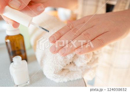 Careful hand care: pushing back cuticles and applying healing polish to strengthen brittle nails. 124038632