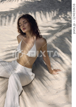 Beautiful girl in sand under palm on a beach Beautiful girl in sand under palm on a beach 124038638
