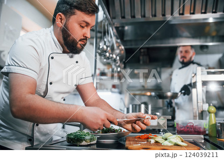 Pouring ingredients. Professional chef preparing food in the kitchen 124039211