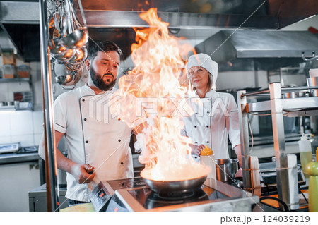 Igniting food in the frying pan. Professional chef preparing food in the kitchen 124039219