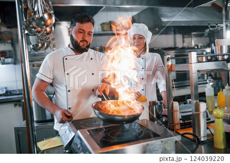 Igniting food in the frying pan. Professional chef preparing food in the kitchen 124039220