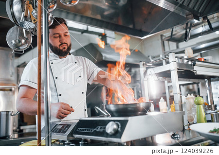 Flames in the frying pan. Professional chef preparing food in the kitchen Flames in the frying pan. Professional chef preparing food in the kitchen 124039226