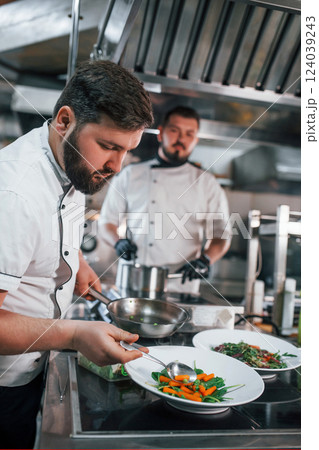 Two brothers is making salad. Professional chef preparing food in the kitchen Two brothers is making salad. Professional chef preparing food in the kitchen 124039243