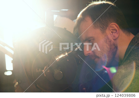 Bearded man examines the sky through telescope lens. 124039806
