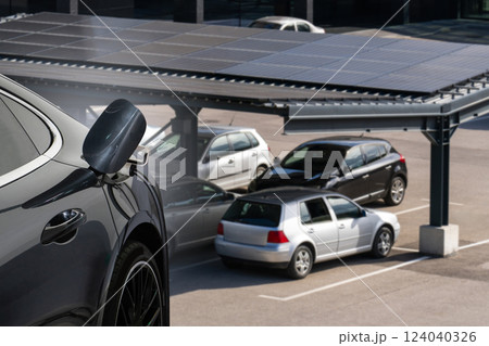 Electric car is charging from a charging station that takes energy from solar panels. Close up 124040326