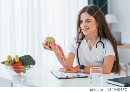 Conception of dieting. Holding apple. Professional medical worker in white coat is in the office 124040477
