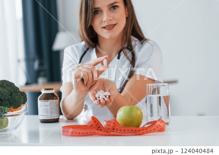 Pills and apple. Professional medical worker in white coat is in the office Pills and apple. Professional medical worker in white coat is in the office 124040484
