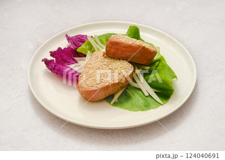 Delicious sesame-coated tuna fish served on a bed of fresh greens with vibrant vegetables 124040691