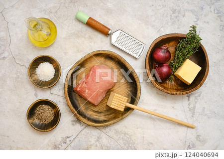 Preparing pork chop with fresh ingredients and tools on a textured surface for cooking 124040694