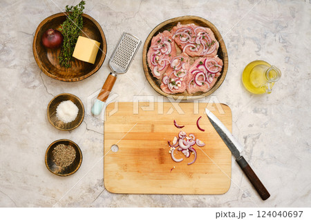 Preparing pork chops with onions and cheese on a wooden cutting board in a modern kitchen 124040697