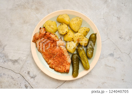 Delicious pork chop served with tender potatoes and pickles on a simple plate Delicious pork chop served with tender potatoes and pickles on a simple plate 124040705