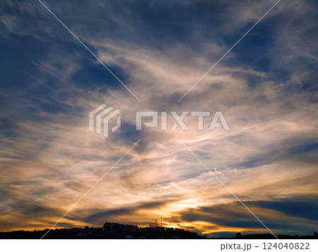 Dramatic sunset sky with layered clouds and silhouetted hills. 124040822
